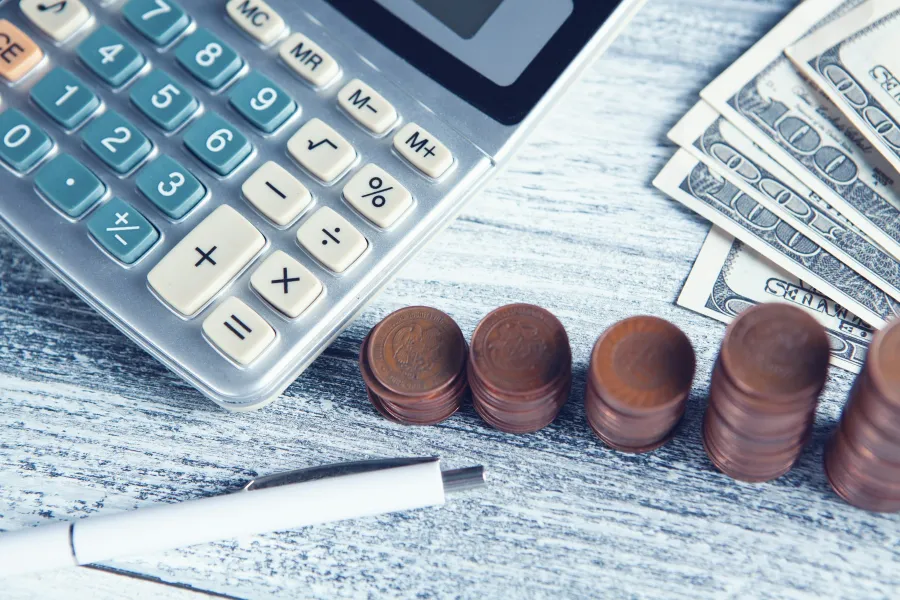 Calculator, coins, and bills on desk in Houston, NJ